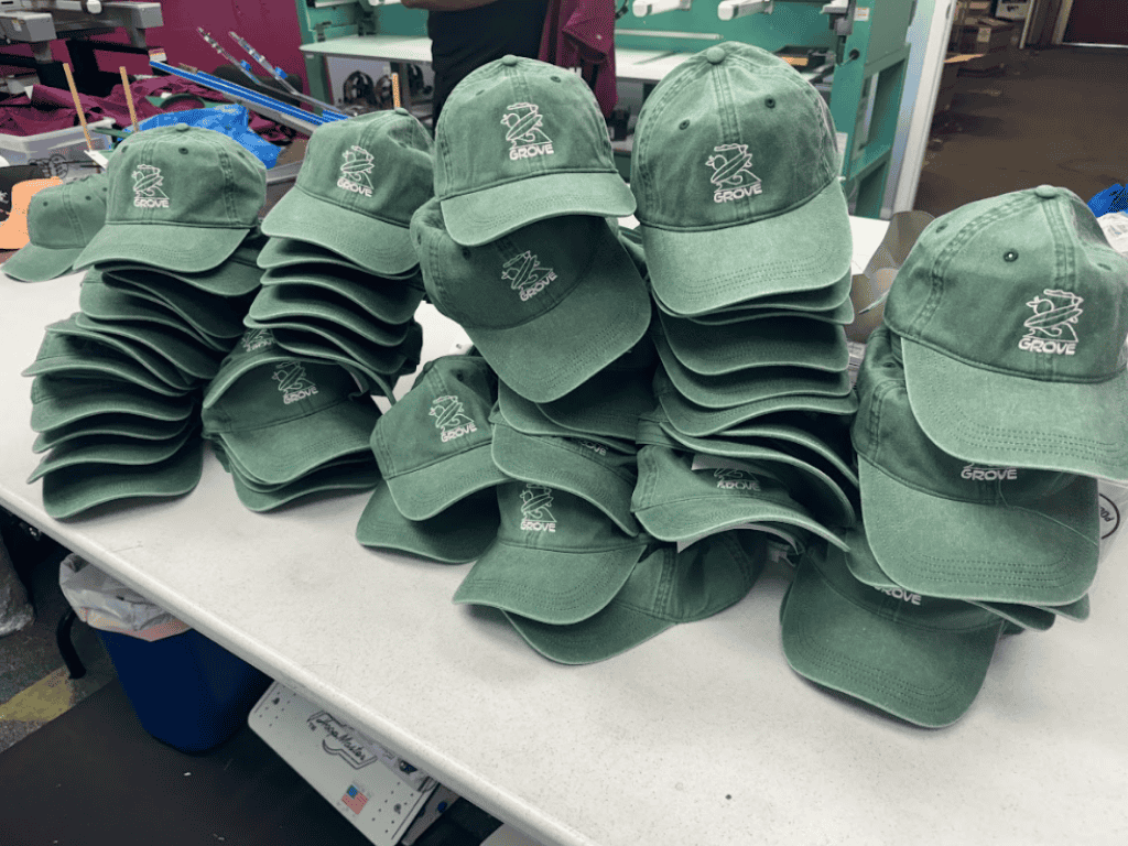 bulk order of custom embroidered green hats stacked on table after production